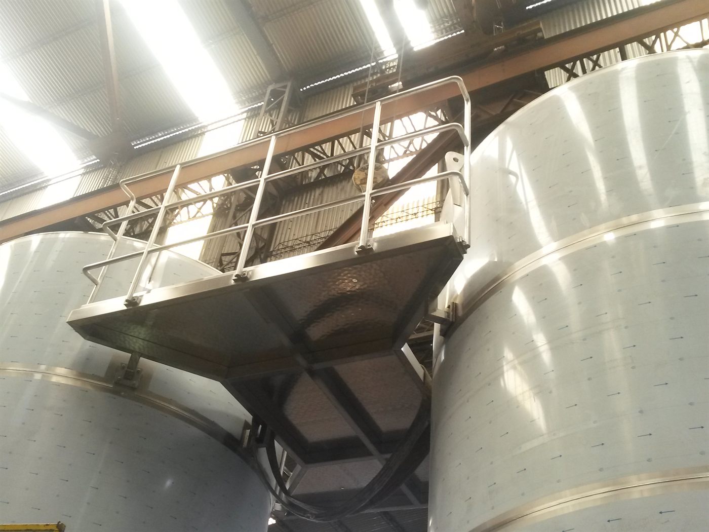 Tanque de acero inoxidable elevado sobre plataforma con baranda de seguridad